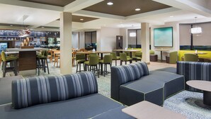 A modern lounge area with seating, a bar, and a large screen. - Courtyard by Marriott Springfield Airport (Springfield)
