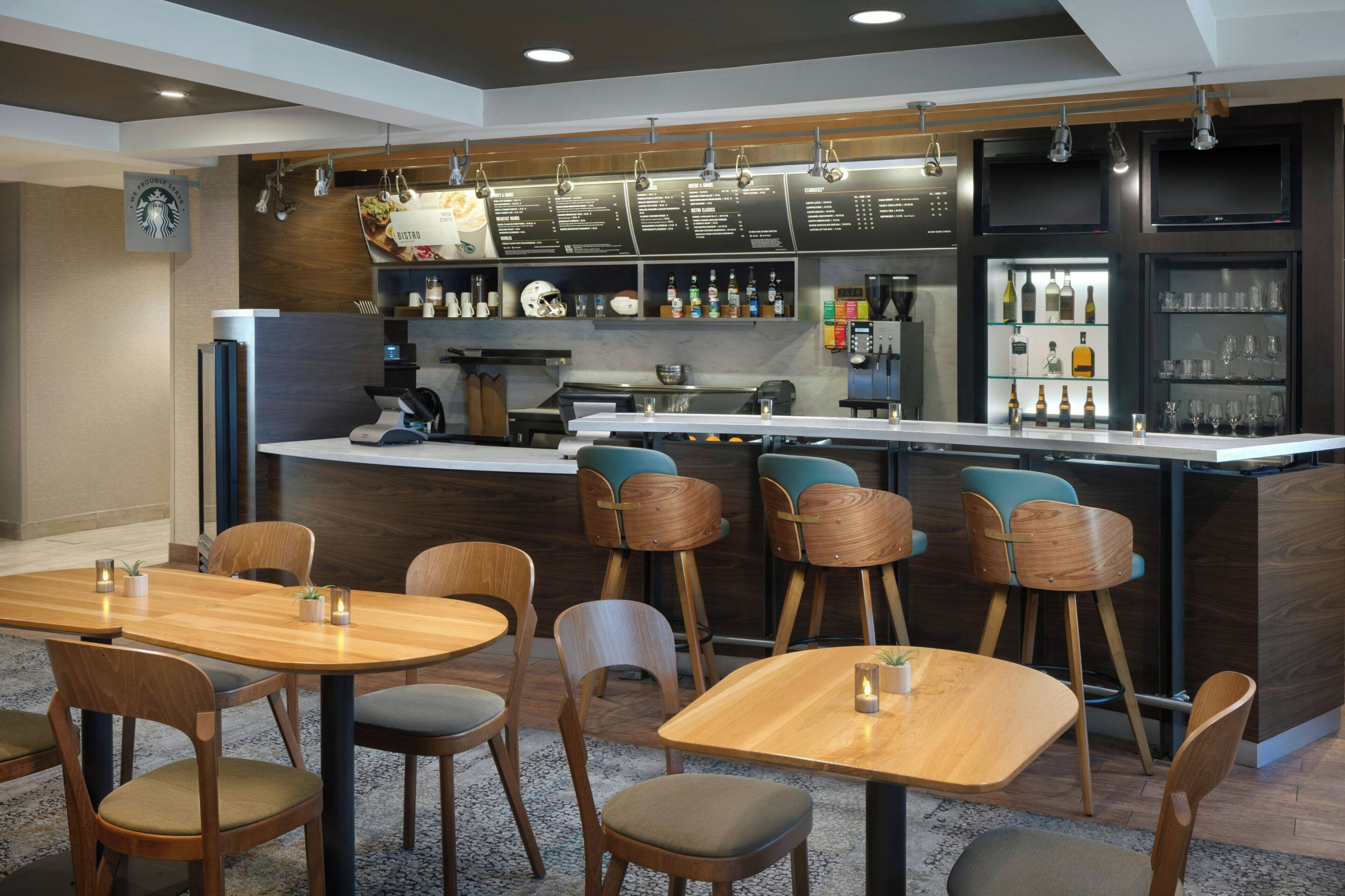 A modern bar area with wooden furniture, a coffee machine, and a menu board.