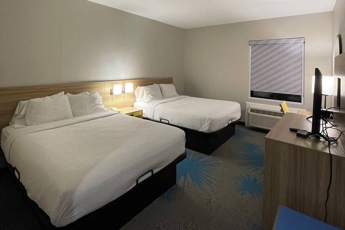 Ein Hotelzimmer mit zwei Betten, einem Schreibtisch und einem Computer.