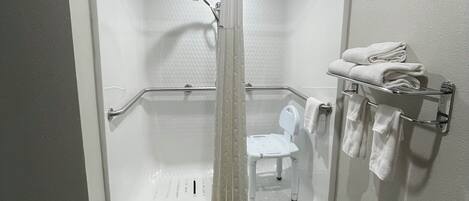 A walk-in shower with a glass door, a white toilet, and a towel rack with folded towels.