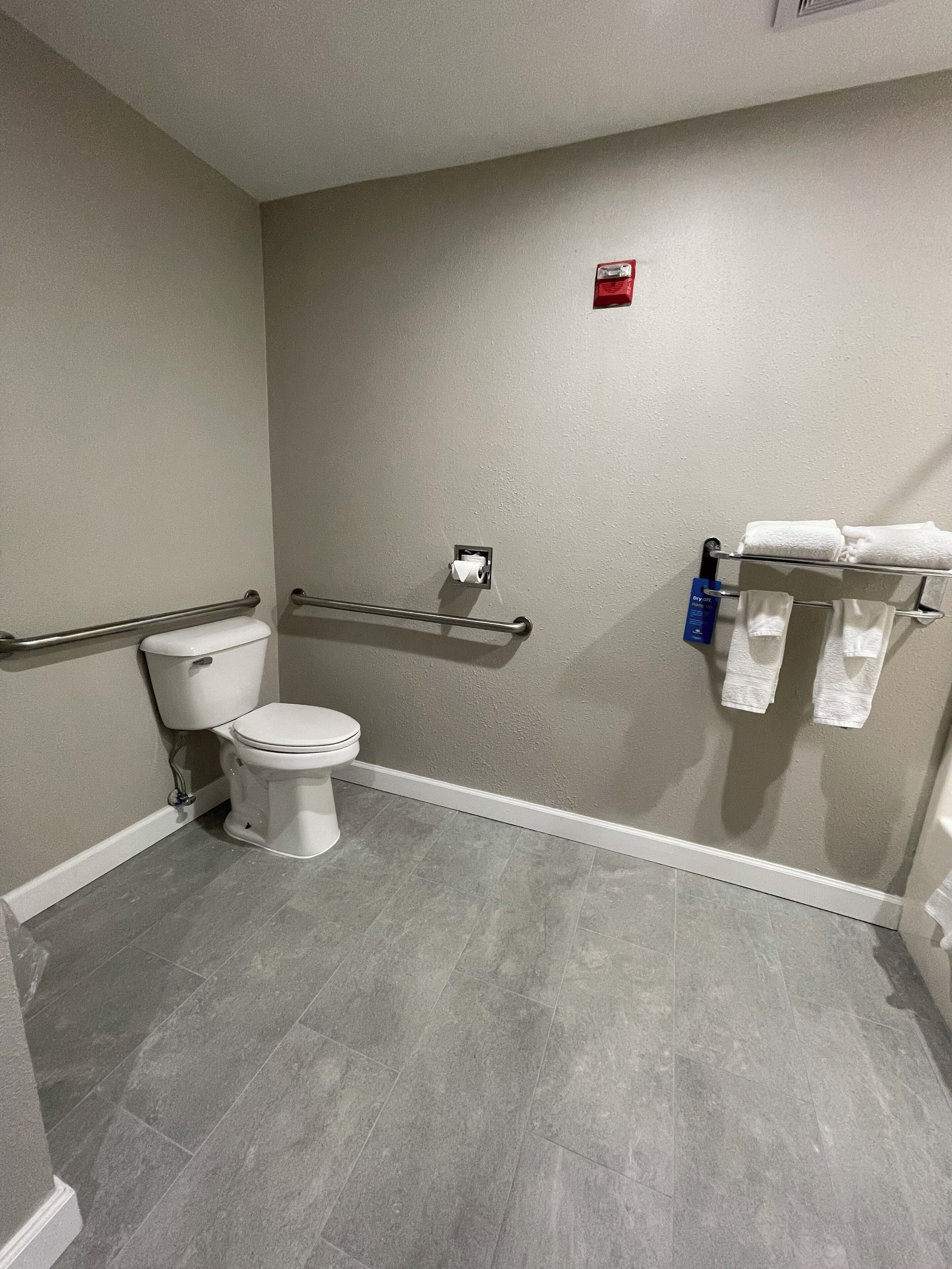 A bathroom with a toilet, a towel rack, and a hand dryer.