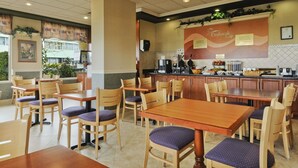 A restaurant with wooden tables and chairs, a kitchen area, and a sign that reads "Daybreak Cafe".