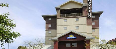 Un hotel Days Inn con un ingresso ben visibile, un balcone al piano superiore e cielo sereno.