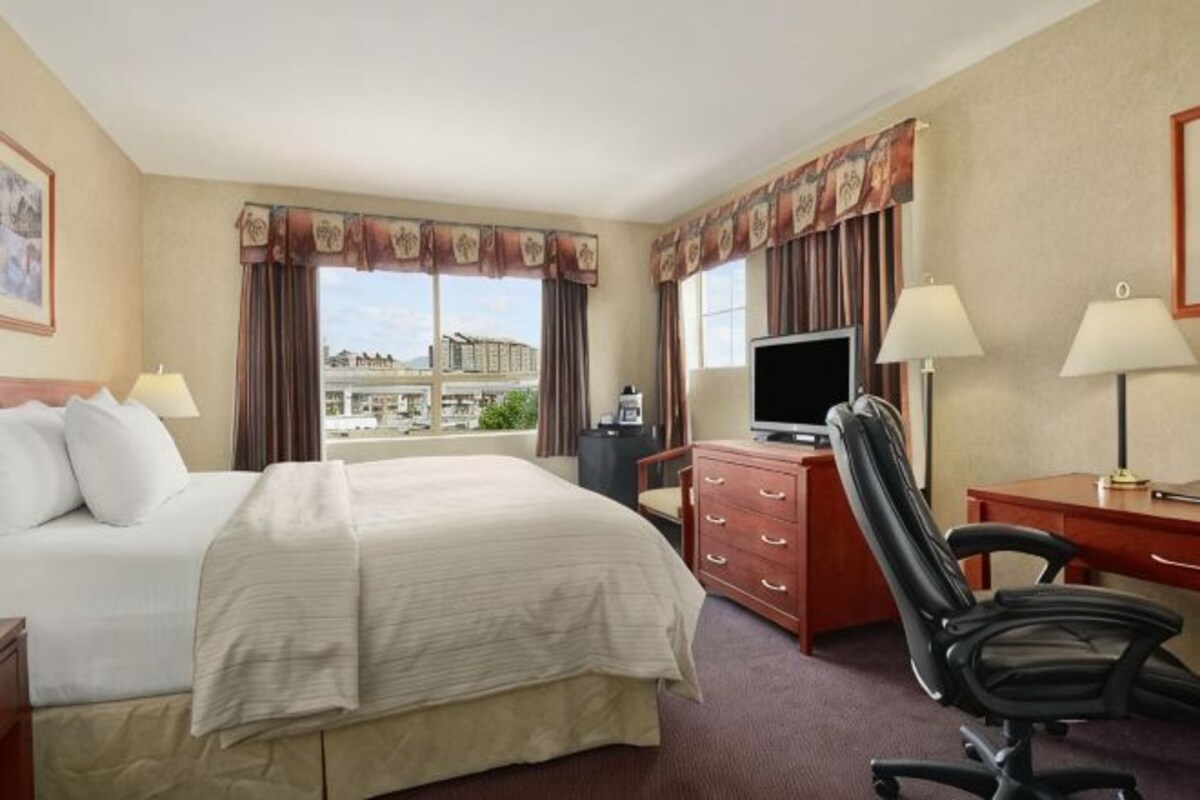 Une chambre d’hôtel équipée d’un lit, d’un bureau, d’une chaise, d’une télévision et offrant une vue sur la ville.