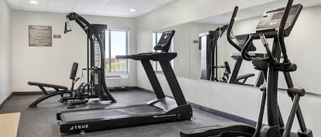 A gym with treadmills, elliptical machines, and a mirrored wall.
