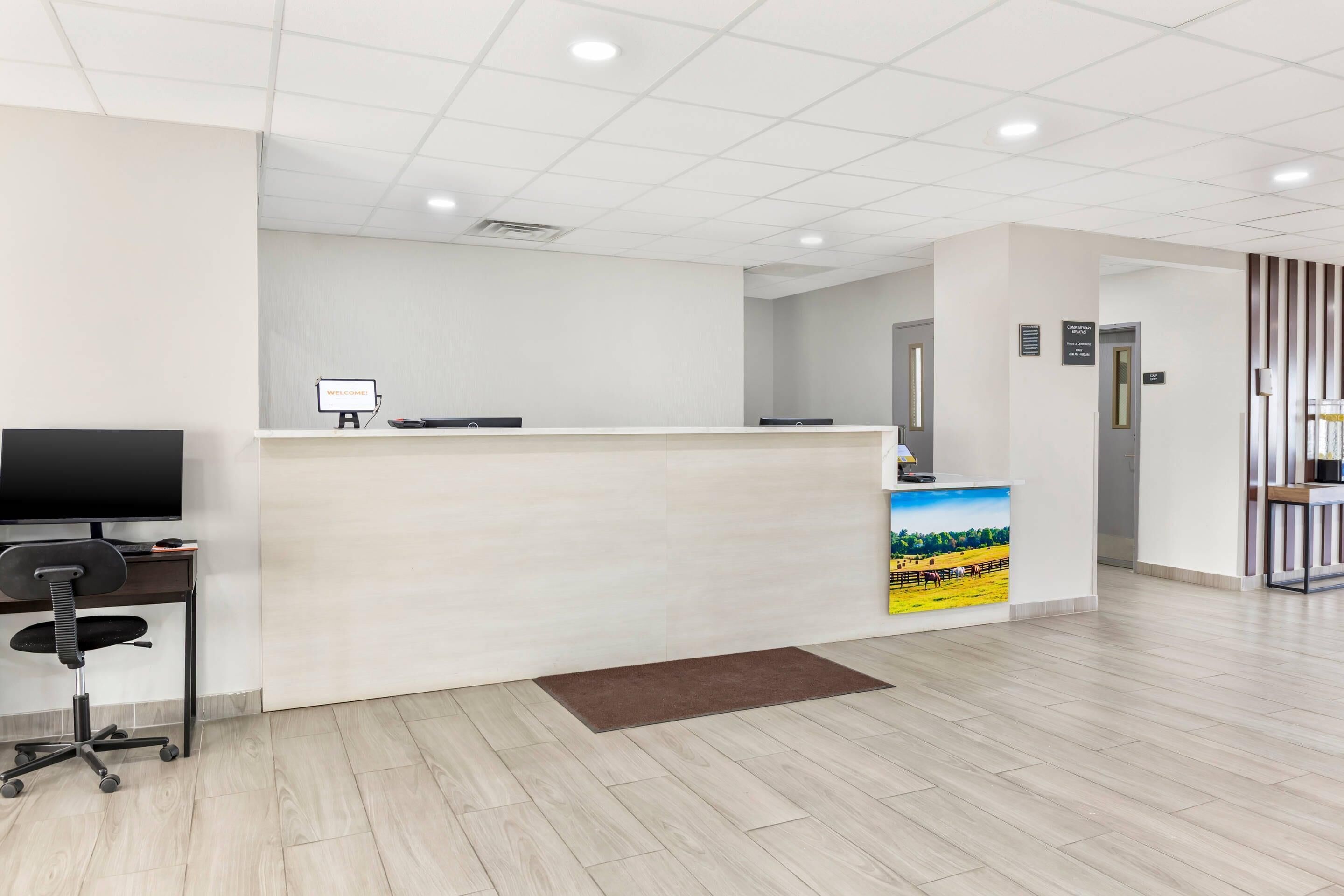 A reception area with a flat-screen TV, a reception desk, and a door leading to another room.