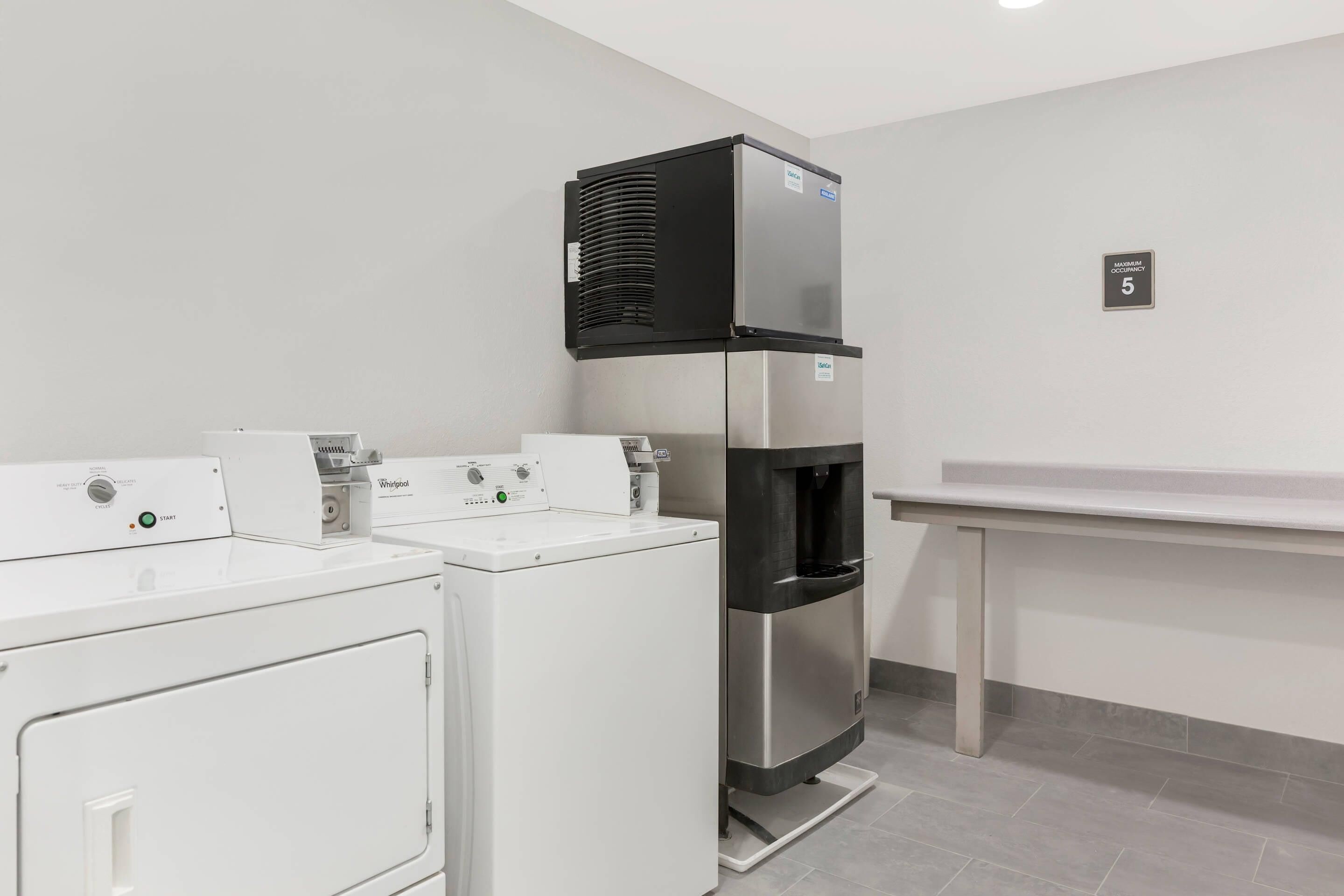A laundry area with a Whirlpool washer and dryer, a water dispenser, and a refrigerator.
