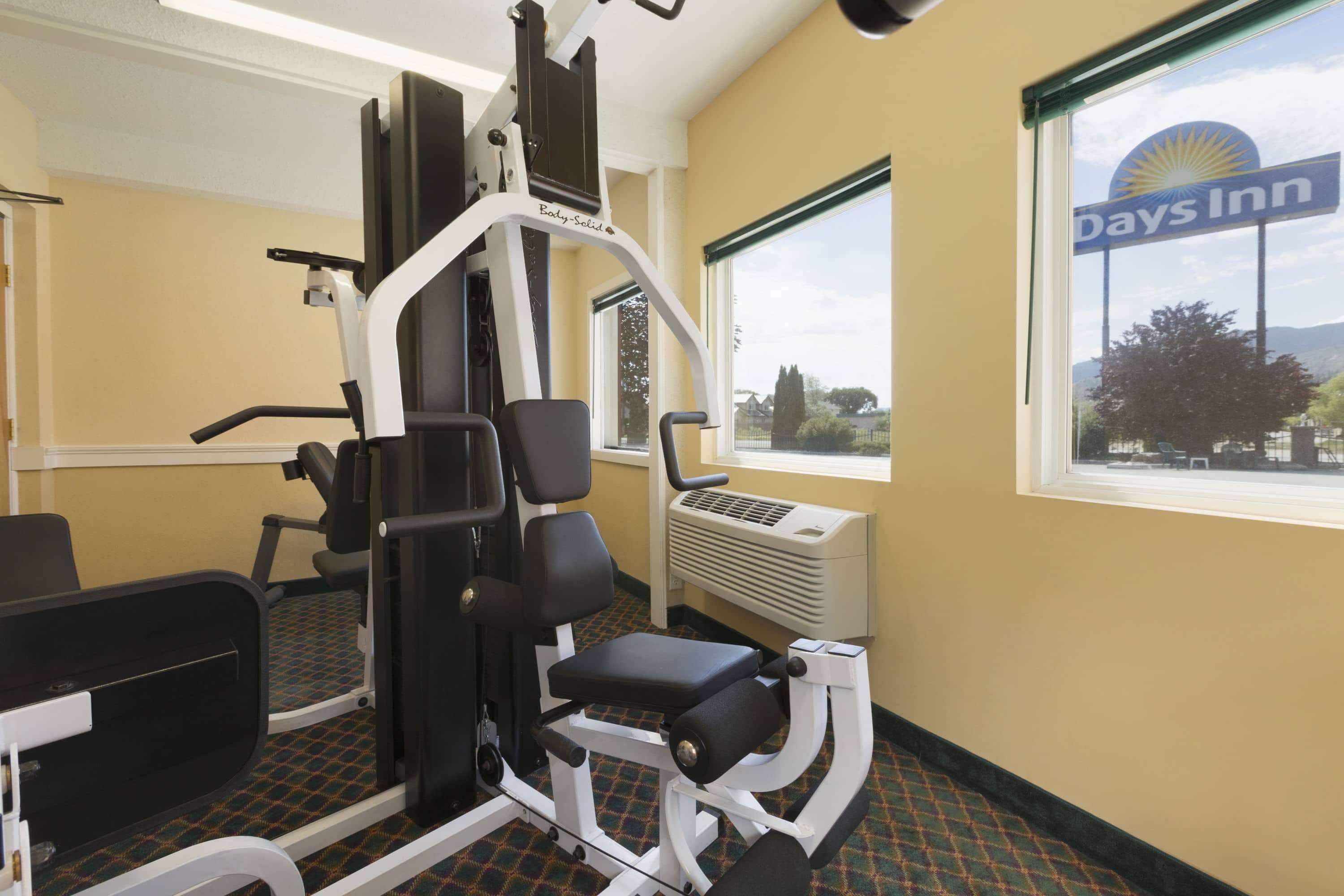 A gym with exercise equipment, a large window with a view, and a sign for Days Inn.