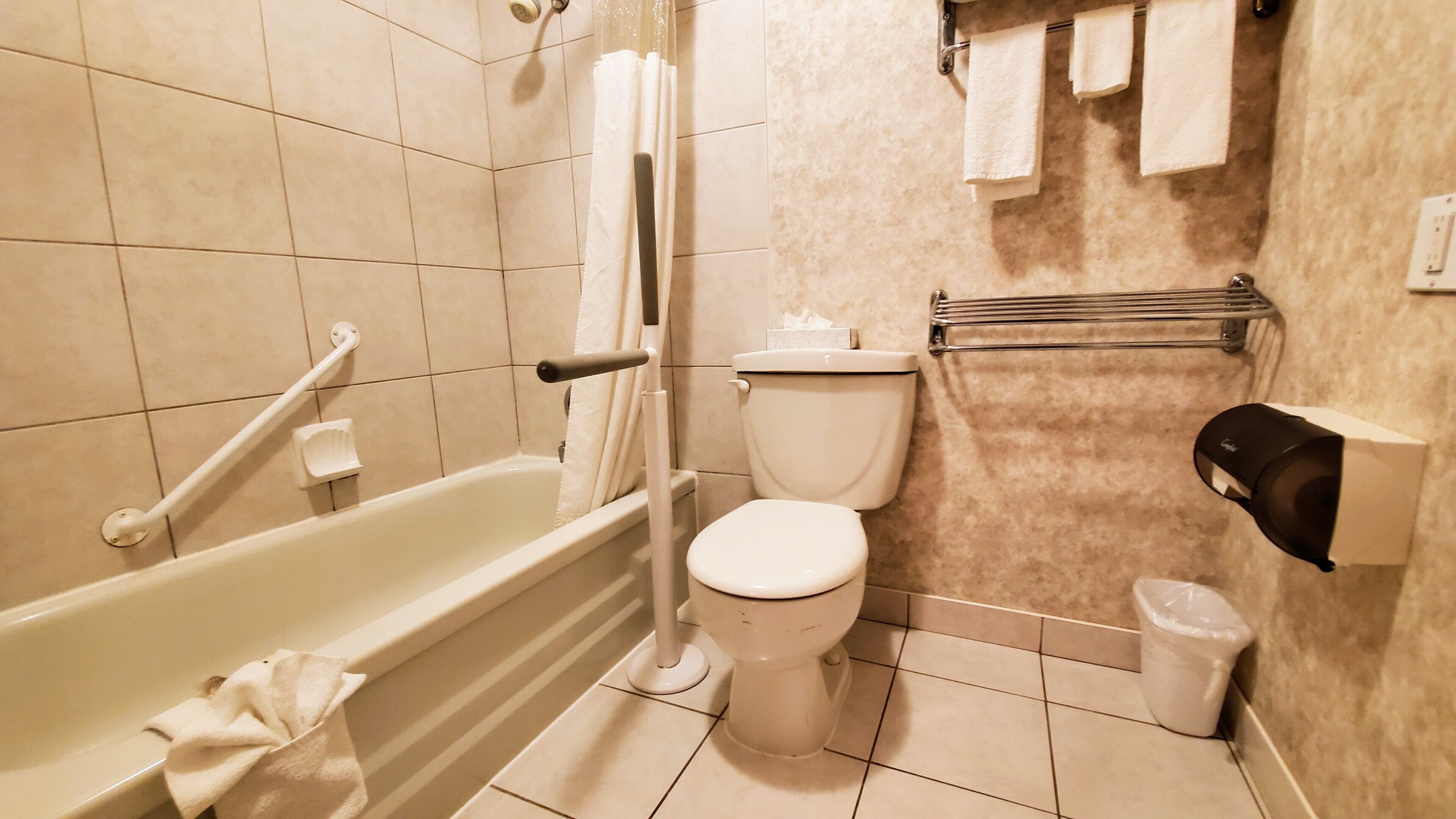 A bathroom with a bathtub, toilet, and hand dryer.