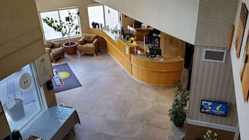 Um hall de hotel com uma recepção, área de estar e uma grande janela.