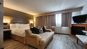 Une chambre d’hôtel avec un lit, un canapé, une télévision et une cheminée.