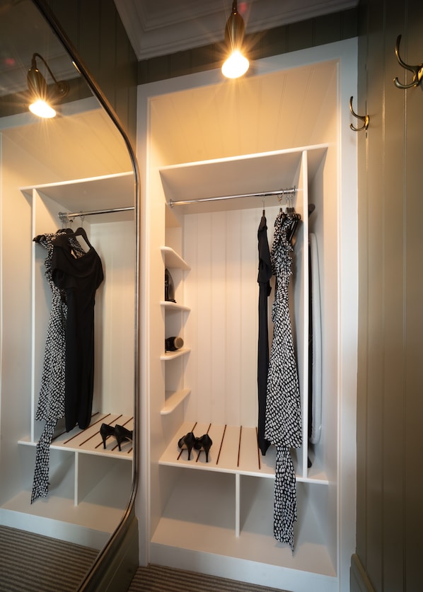 A walk-in closet with white shelving, a mirror, and hanging clothes. - Eleven Didsbury Park (Manchester)