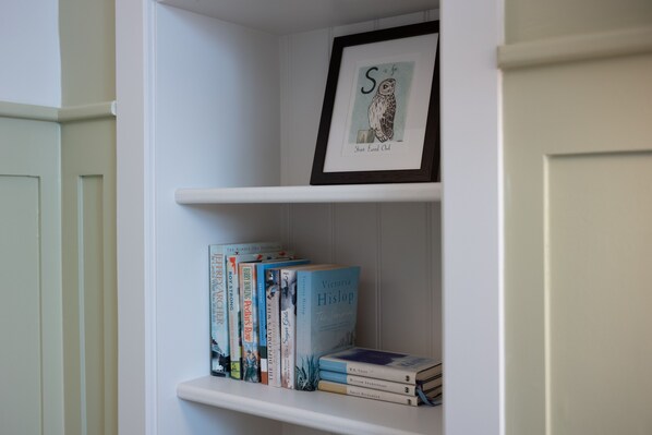 A bookshelf with books and a framed picture of an owl. - Eleven Didsbury Park (Manchester)