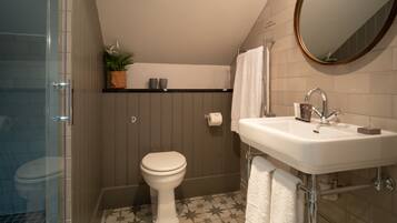 Une salle de bain équipée d’une douche, de toilettes, d’un lavabo et d’un miroir.