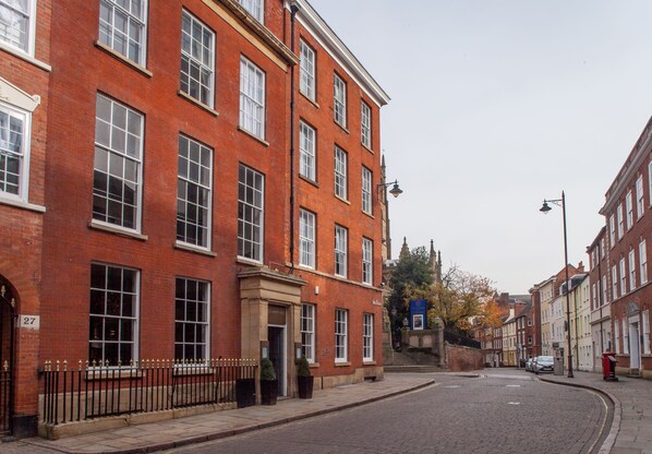 A red brick building with multiple windows and a door, a cobblestone street, and a clear sky. - Lace Market Hotel (Nottingham)