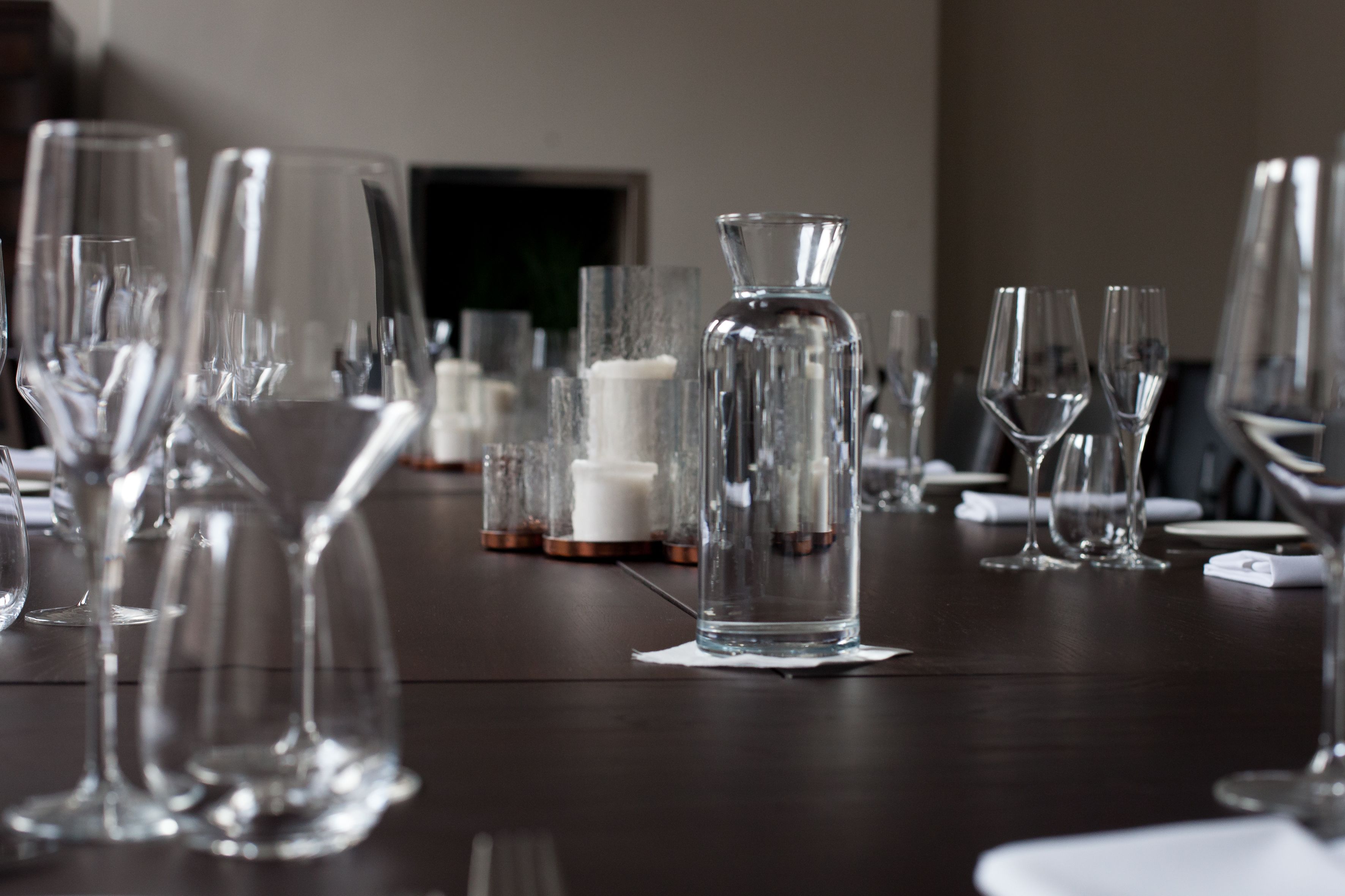 A table set with various glassware and a candle holder, indicating a formal dining arrangement.