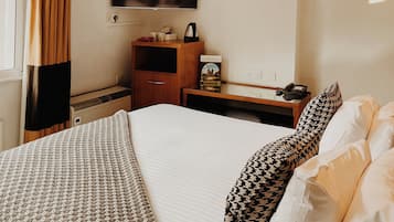 A hotel room with a bed, a TV, a desk, a lamp, and a ceiling fan.