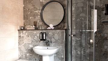 A bathroom with a glass-enclosed shower, a pedestal sink, and a toilet.