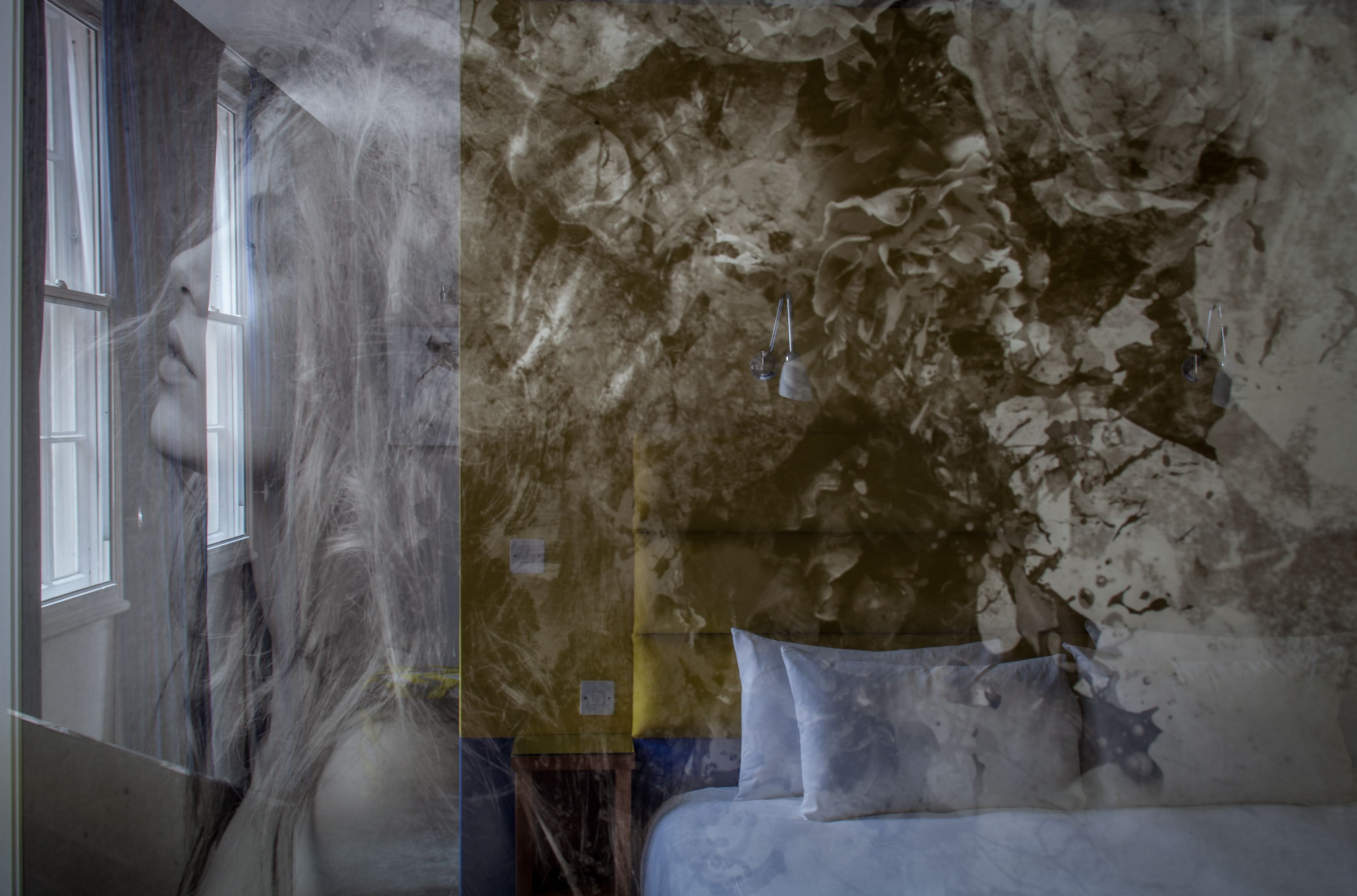 A bedroom with a bed, a window, and a wall with peeling paint.