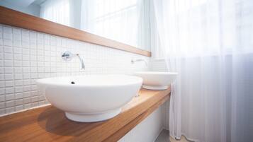 Un baño con dos lavamanos blancos, encimera de madera y un espejo sobre los lavamanos.