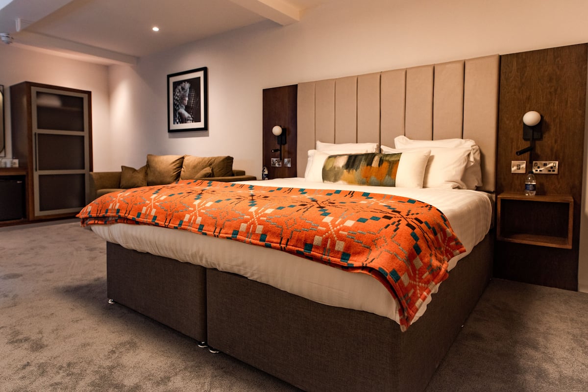 A modern bedroom with a large bed, a wooden headboard, and a built-in bench.