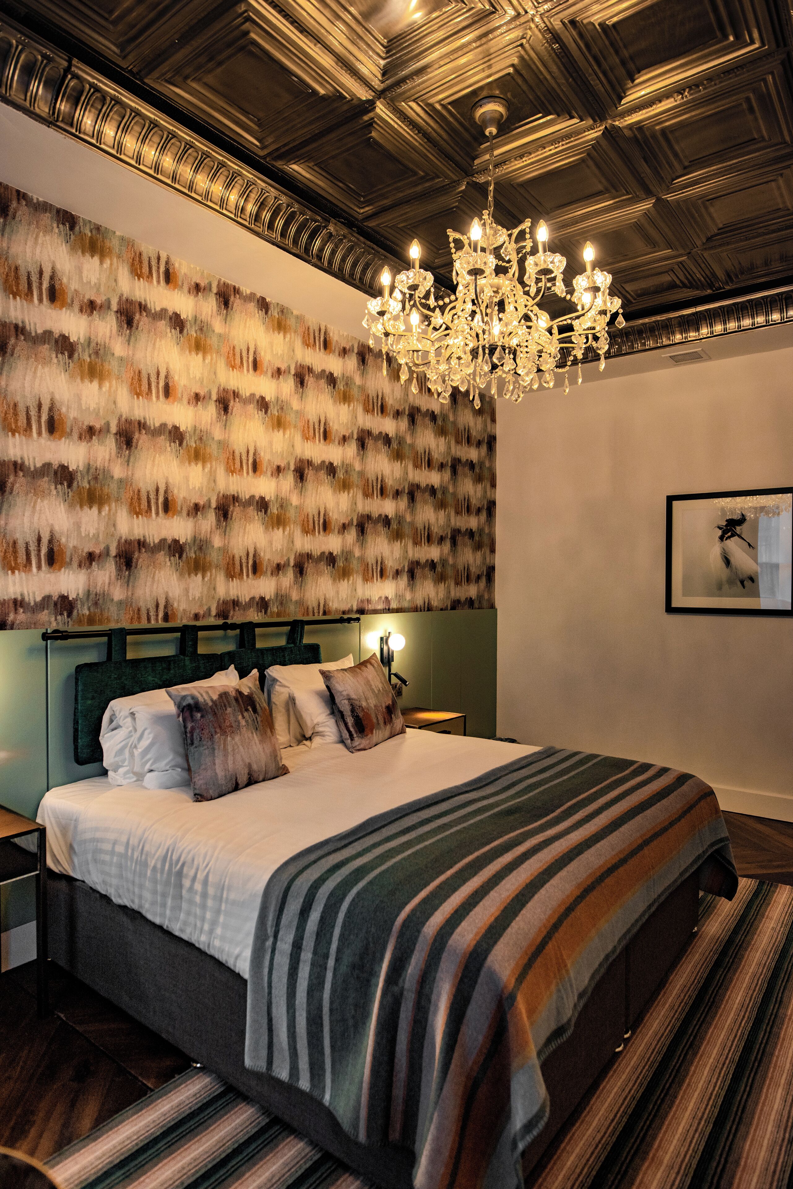 A modern bedroom with a large bed, a chandelier, and a textured wall.