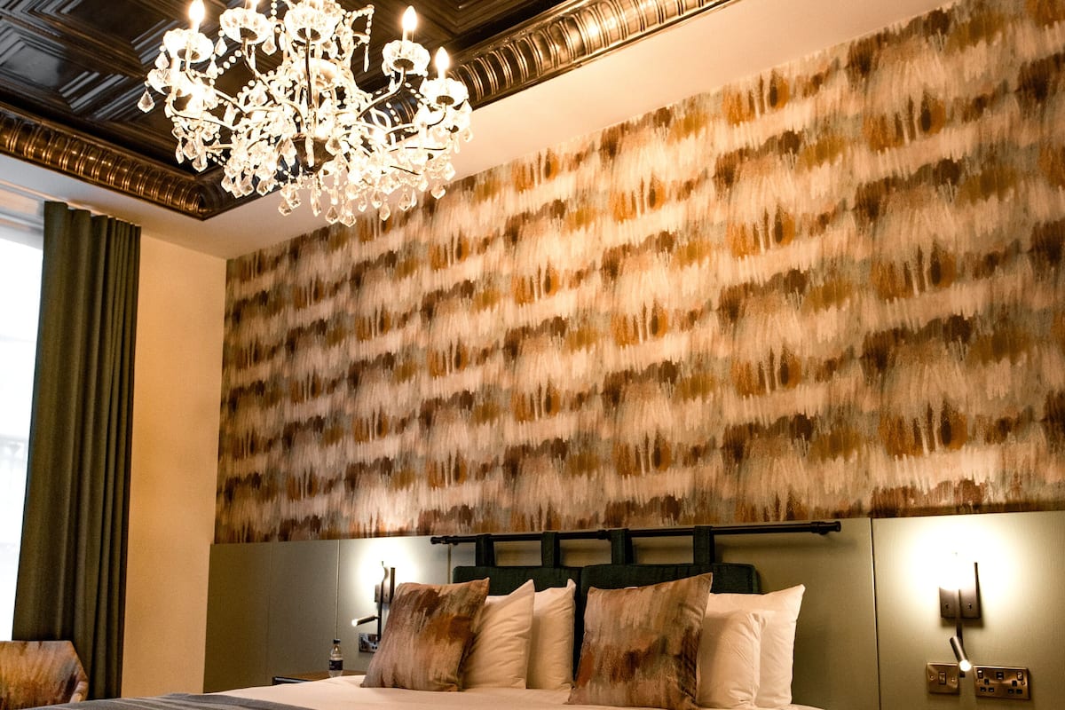 A hotel room with a large bed, a desk, and a chandelier.