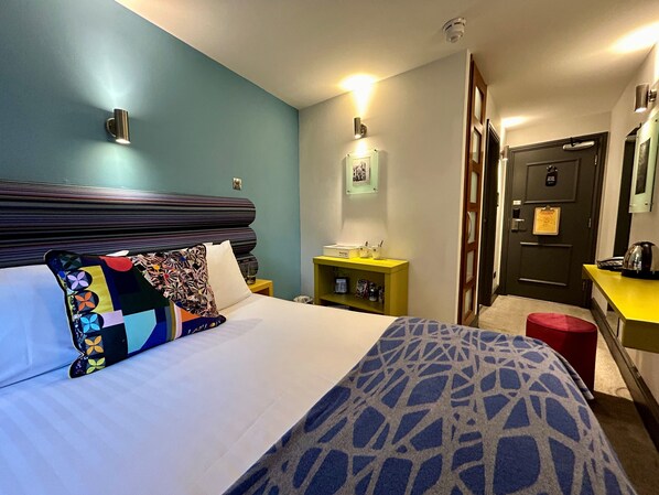 A hotel room with a bed, a nightstand, a desk, and a door. - Lace Market Hotel (Nottingham)