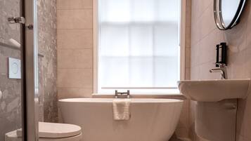 A bathroom with a freestanding bathtub, a toilet, and a sink.