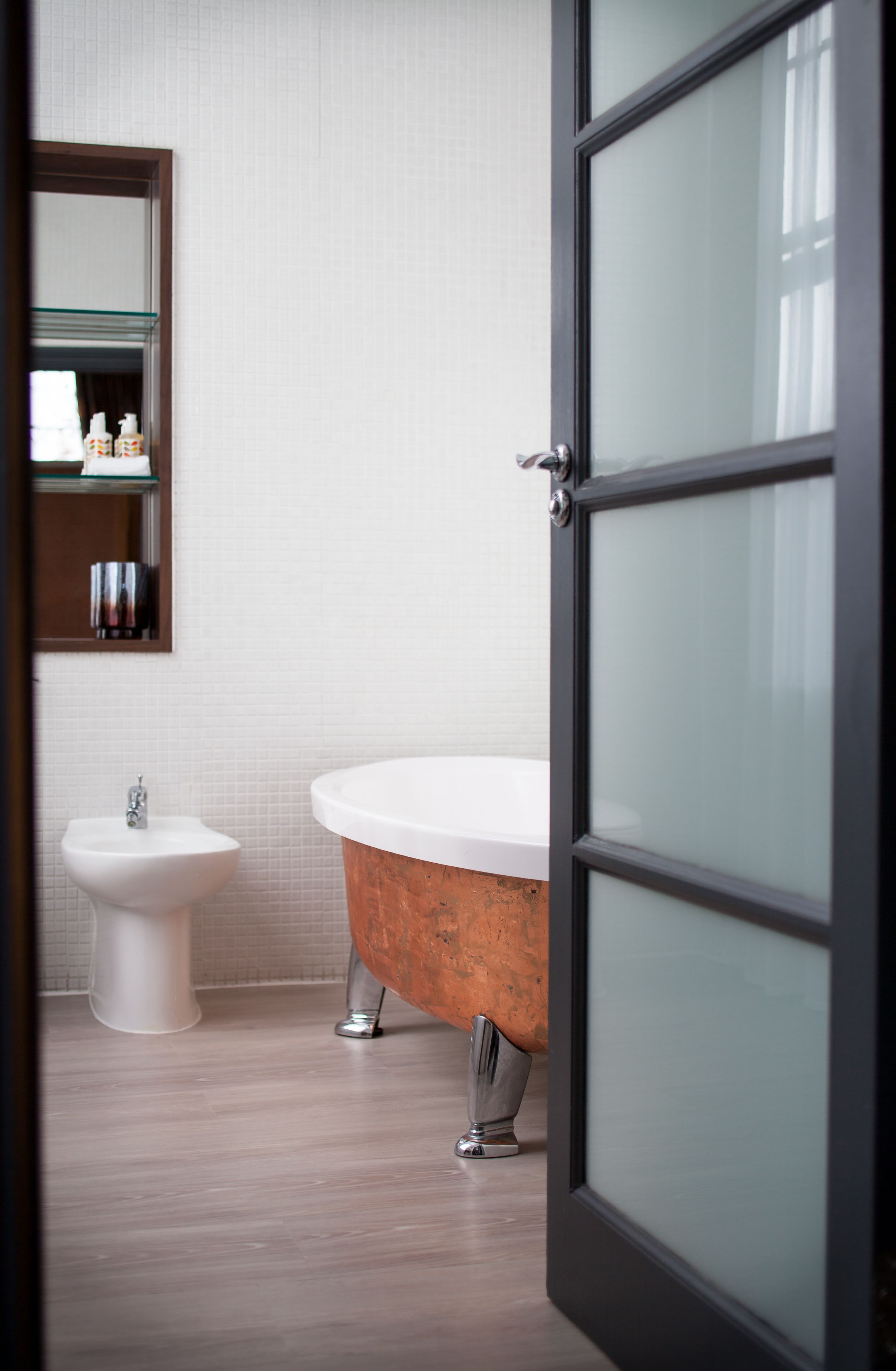 Un baño moderno con una bañera independiente, un lavamanos pedestal y una zona de ducha con mampara de cristal.