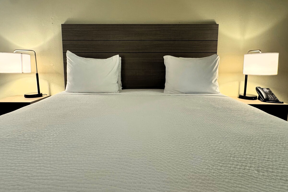 Una habitación de hotel con una cama grande, dos lámparas de noche y un teléfono en la mesita.