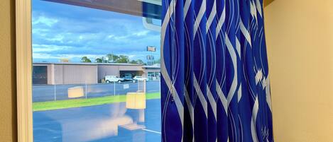 A window with a view of a parking lot and a building with a sign.
