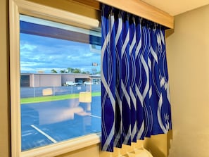 A window with a view of a parking lot and a building with a sign. - Travelodge by Wyndham Thomasville AL (Thomasville)