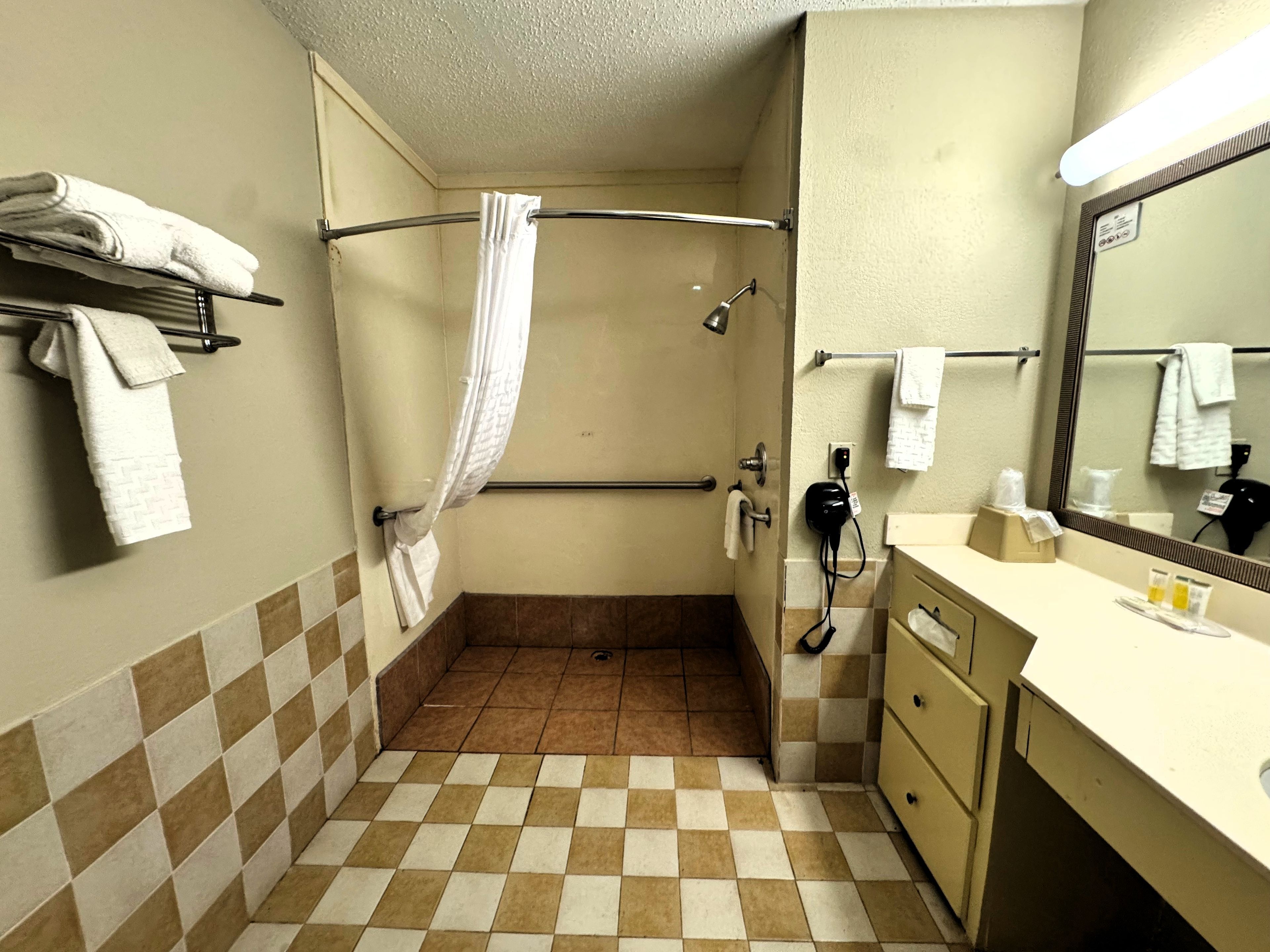 Une salle de bain équipée d’une douche, de toilettes, d’un lavabo avec des articles de toilette et d’un miroir.