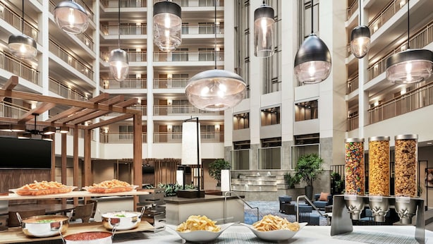 A spacious hotel lobby with multiple dining tables, buffet stations, and hanging pendant lights. - Embassy Suites by Hilton Columbus Dublin (Dublin)