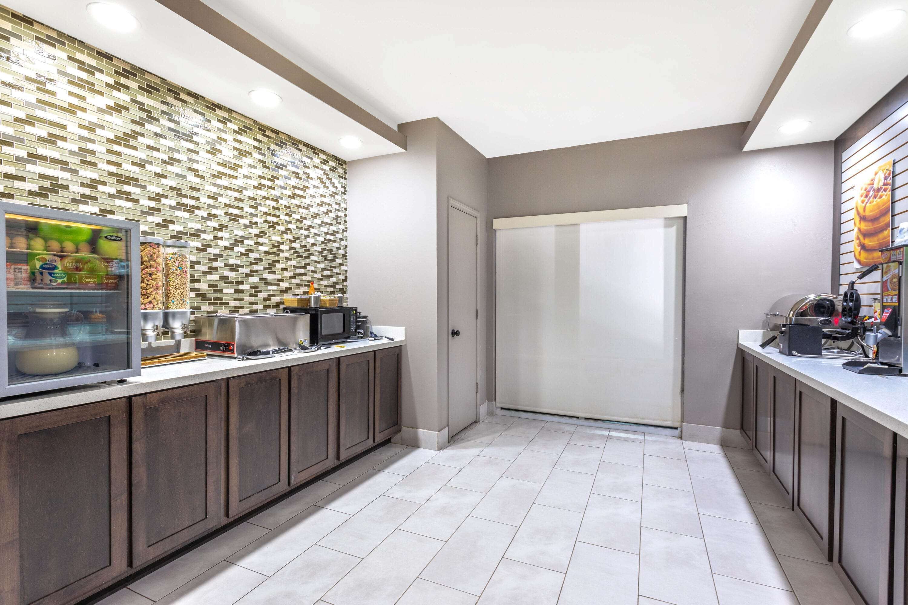 A modern kitchen with a built-in refrigerator, microwave, and coffee machine.