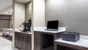 Un espace d’accueil d’hôtel comprenant un comptoir, un ordinateur portable, une imprimante et une machine à café.