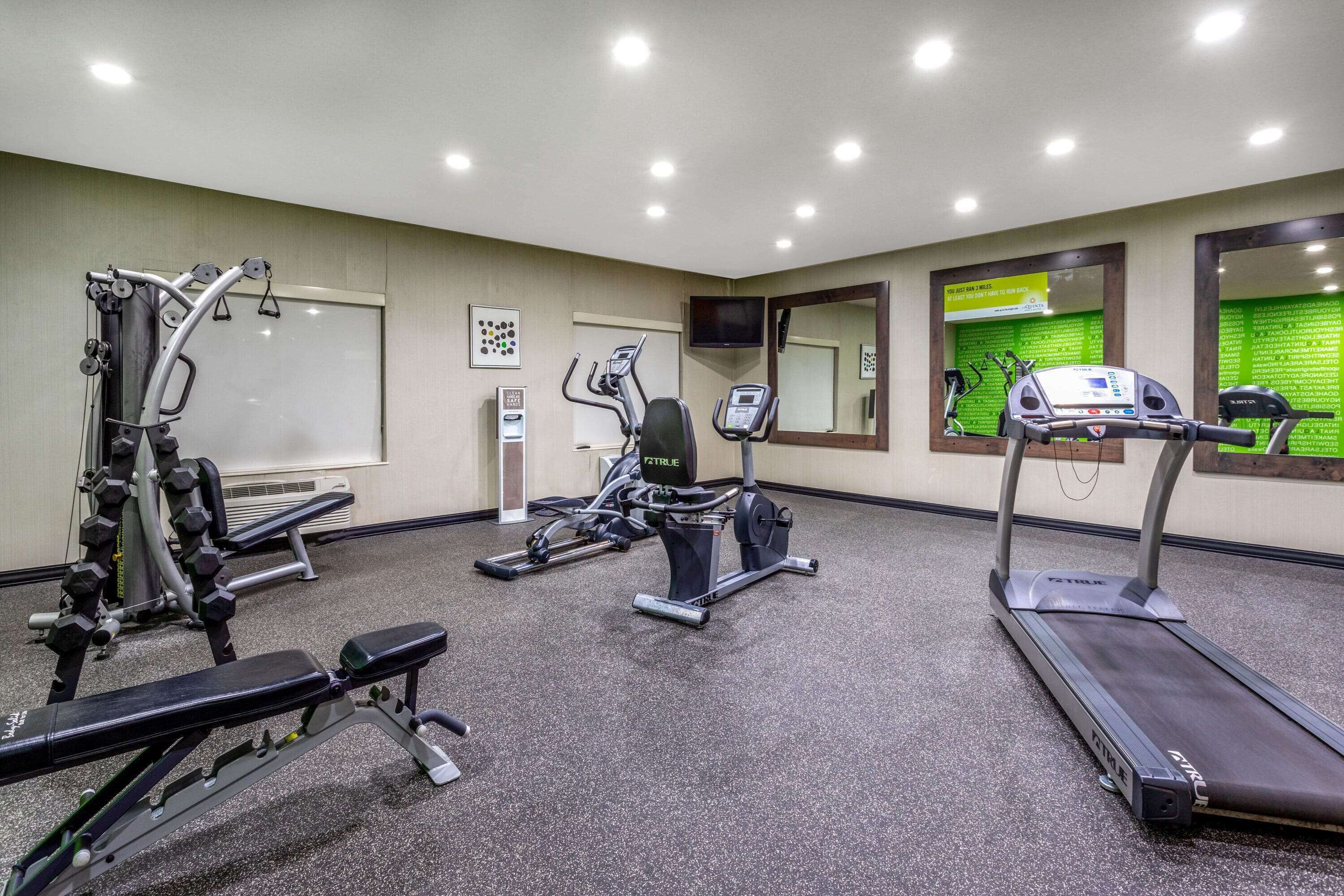 A gym with treadmills, elliptical machines, and weight benches.