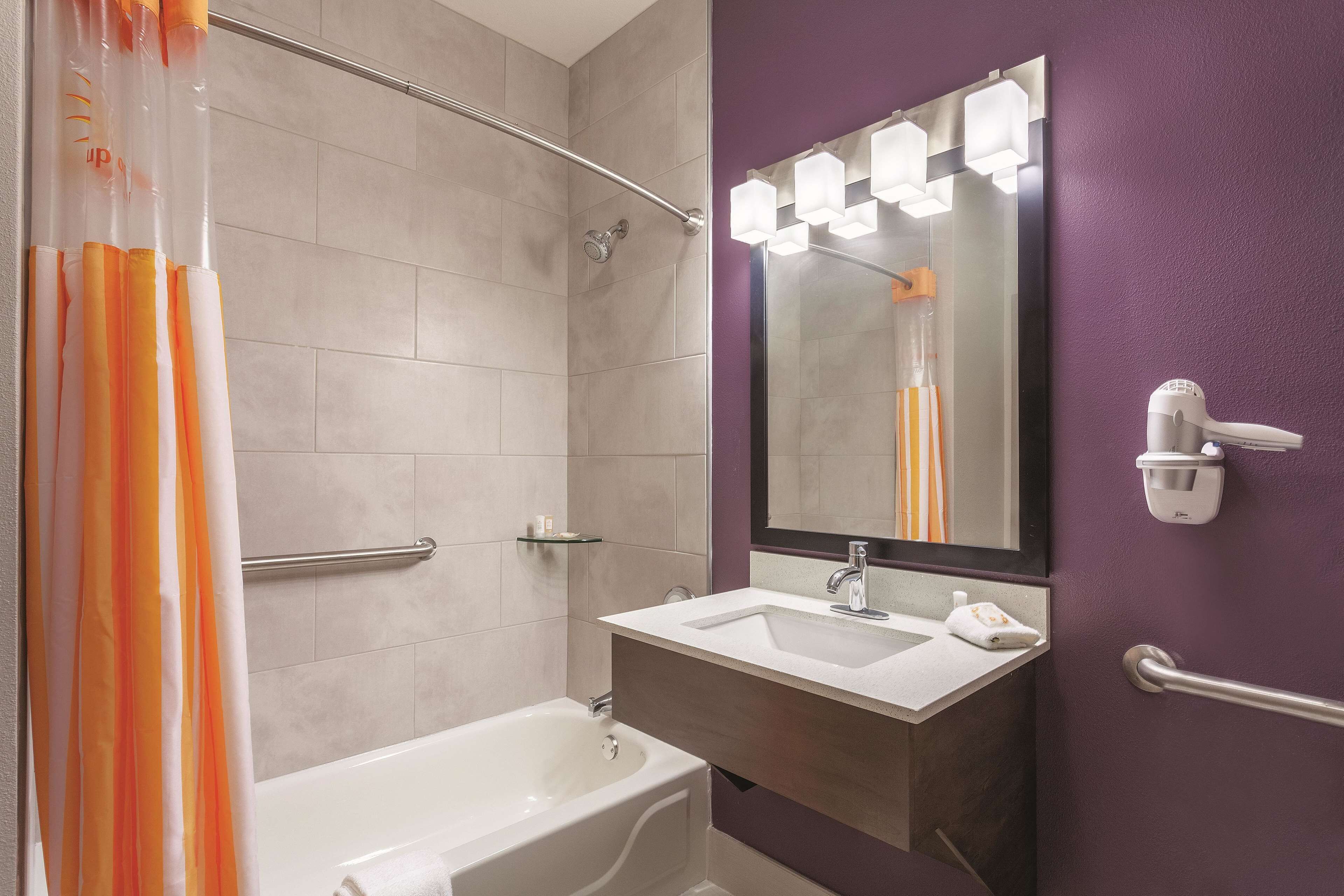 Un baño con bañera, lavamanos, espejo con iluminación y zona de ducha.