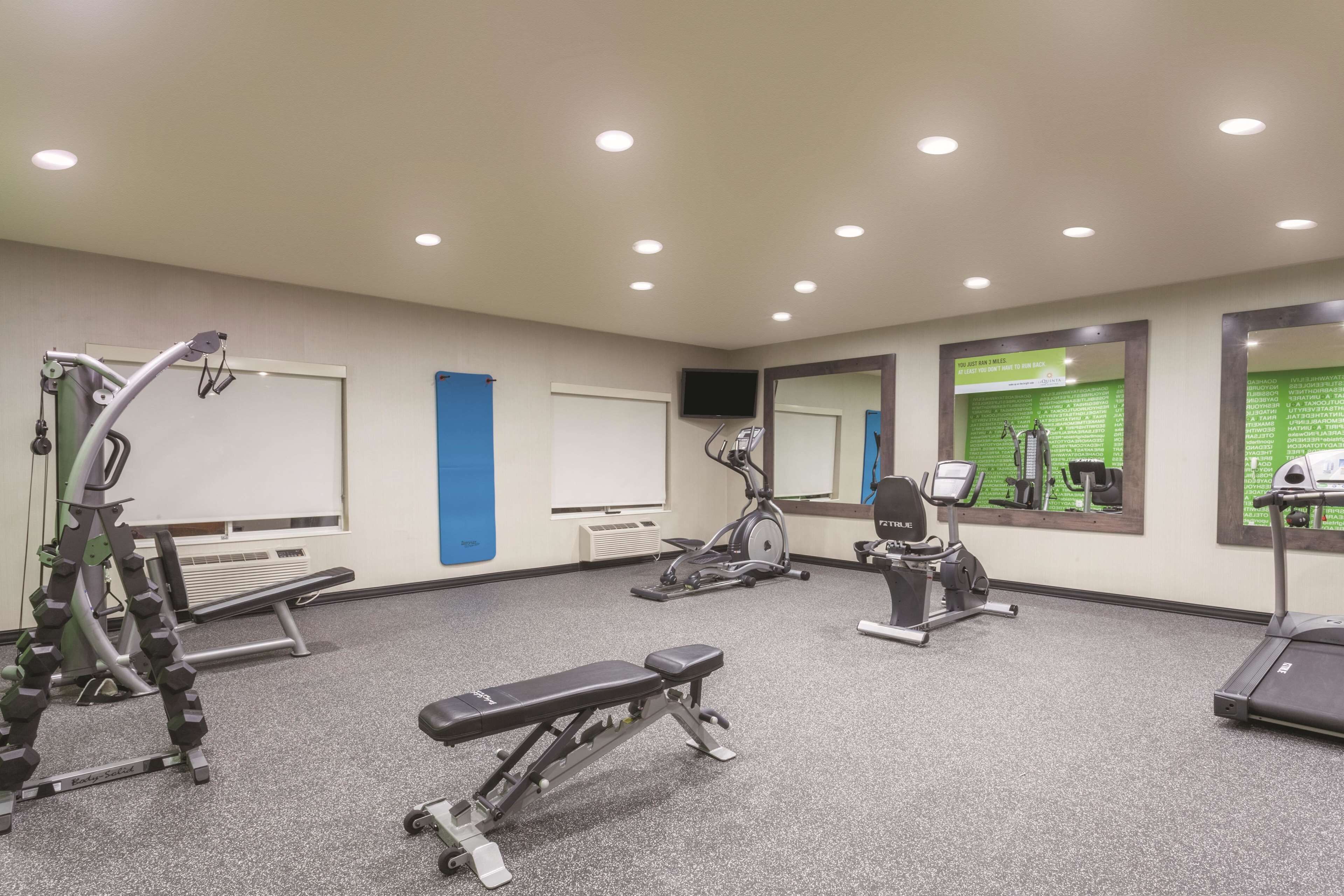 A gym with various exercise equipment, including a treadmill, stationary bike, and weight bench.