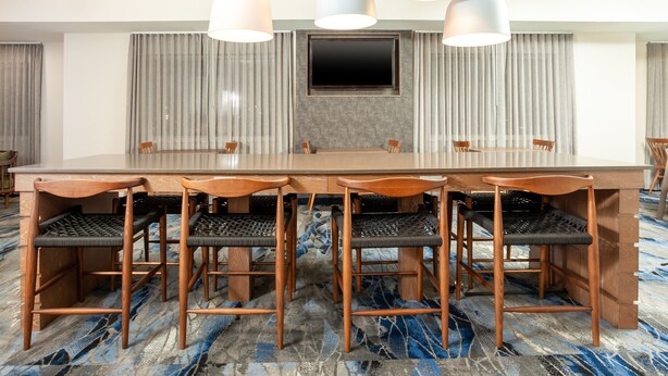 A conference room with a long table, six chairs, and a large flat-screen TV.