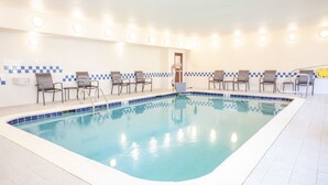 An indoor swimming pool with a tiled border, multiple lounge chairs, and a tiled wall with a checkered pattern. - Fairfield inn by Marriott North Little Rock (North Little Rock)