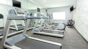 A modern fitness center with treadmills, exercise bikes, and a mirrored wall.