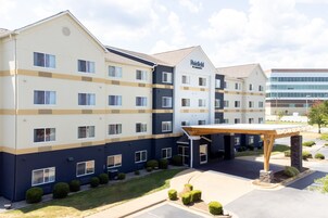 Un hotel de varios pisos con un diseño moderno, que cuenta con una entrada cubierta y un área de estacionamiento.