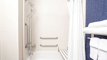 Un baño con bañera, ducha y barras de apoyo.