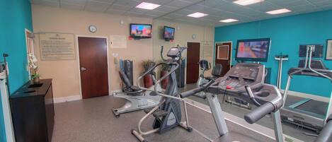 Un gimnasio con cintas de correr, bicicletas estáticas y equipo de ejercicio.