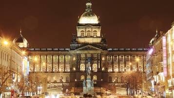 Un edificio grande e iluminado, con una cúpula destacada y estatuas en la fachada.
