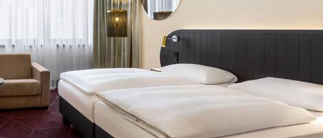 A hotel room with two beds, a chair, and a large mirror.
