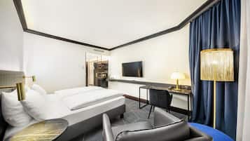 Una habitación de hotel con una cama, un escritorio, una silla, un televisor y una lámpara.