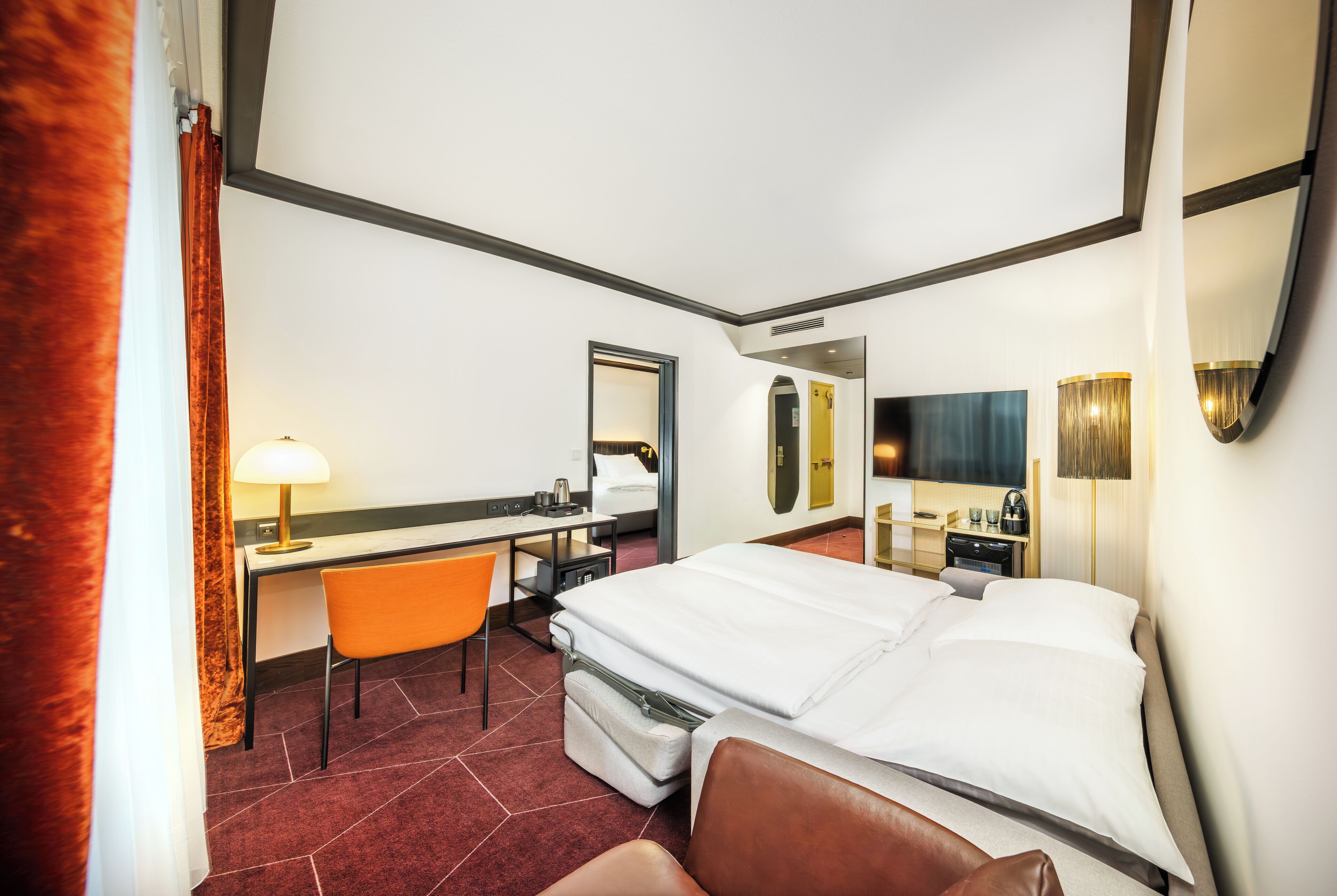 Habitación de hotel con cama, escritorio, silla y espejo.